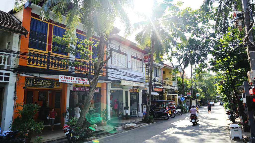 Colourful Phuket street with palm trees and local life.