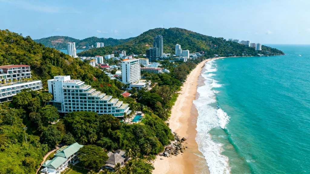 Phuket coastline with modern buildings and turquoise waters.