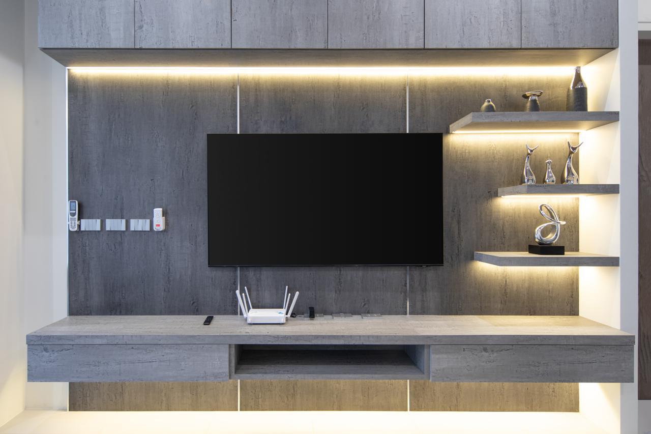 Modern gray wall unit with a large flat-screen TV, a floating console, and lit shelves displaying metallic sculptures.