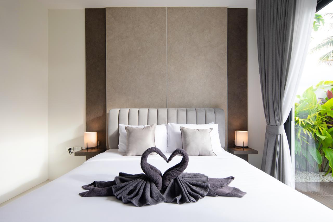 Bed with white linens and a decorative pair of towel swans forming a heart at the center of the mattress.