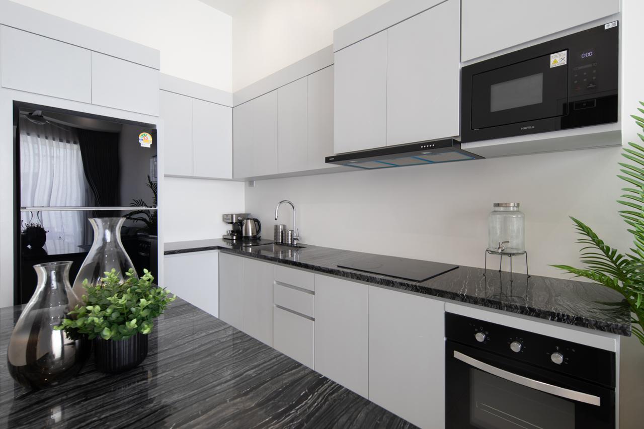 Modern gray kitchen with black marble countertops, built-in oven and microwave, and a sink along the counter. (Informative)