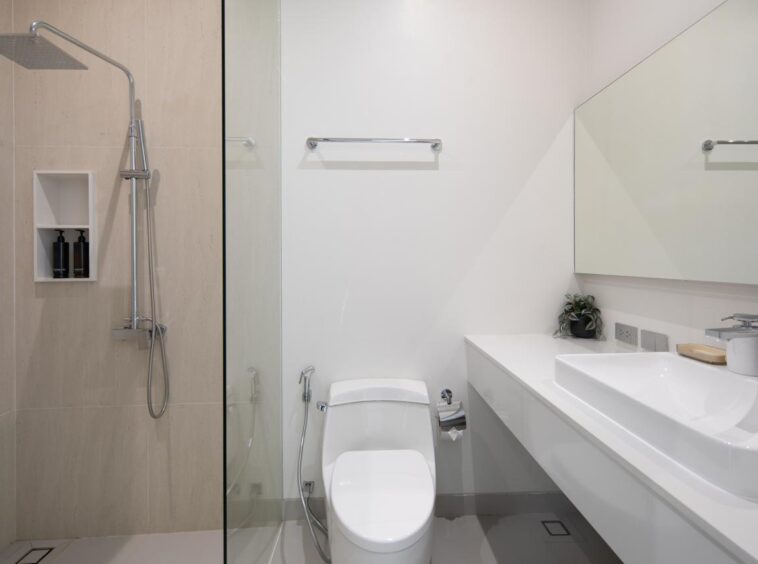 Modern bathroom with a glass shower enclosure, wall-mounted sink, and toilet in a bright, minimal design.
