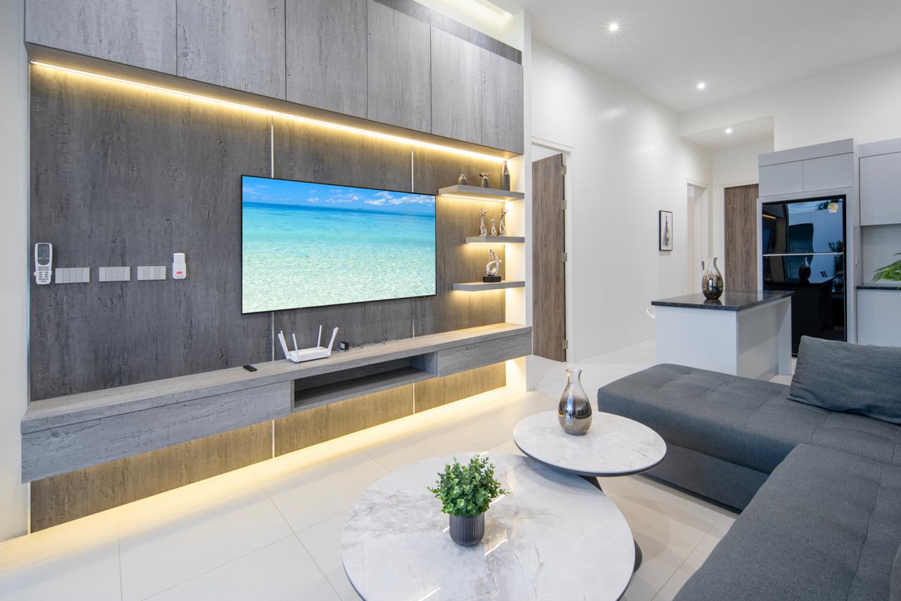 Contemporary living room with a wall-mounted TV on gray wood paneling, illuminated shelves, and a gray sectional sofa.