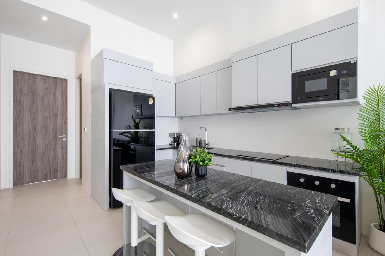 Modern white kitchen with a black marble island, bar stools, and stainless appliances.