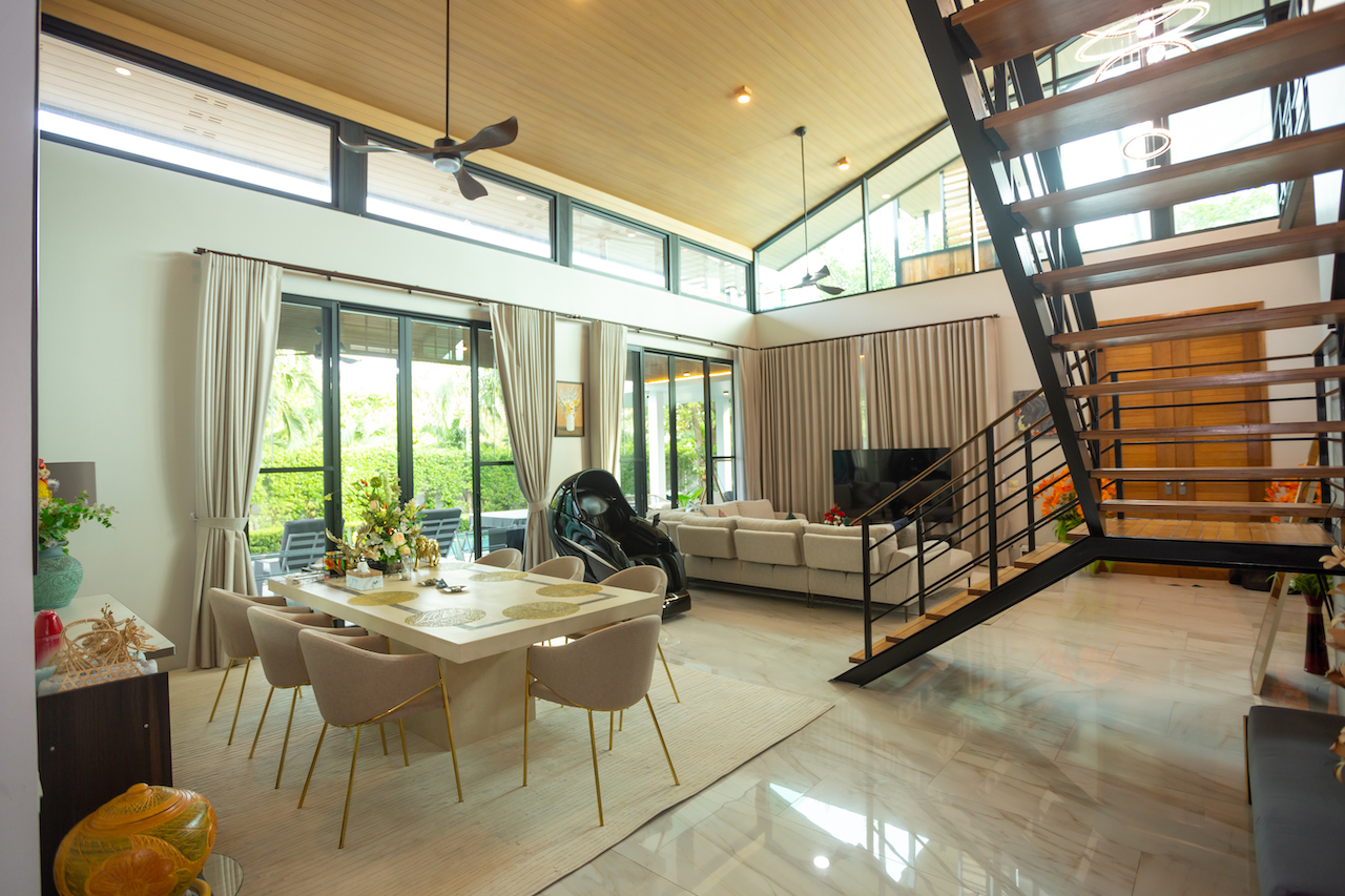 Open-plan living and dining area with a large glass door patio, beige dining table and eight chairs, and a black metal staircase to the right.