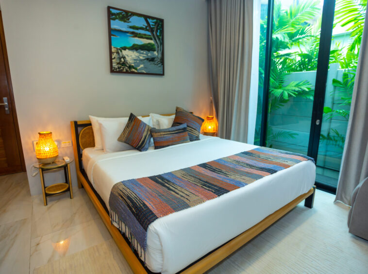 Hotel bedroom with a king bed, colorful striped runners and pillows, and warm bedside lamps.