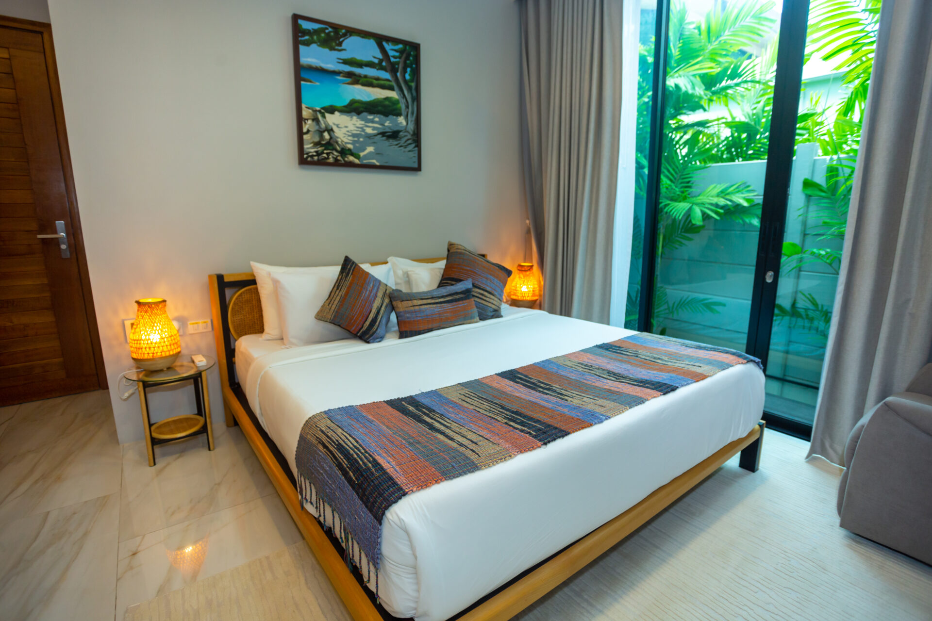 Hotel bedroom with a king bed, colorful striped runners and pillows, and warm bedside lamps.