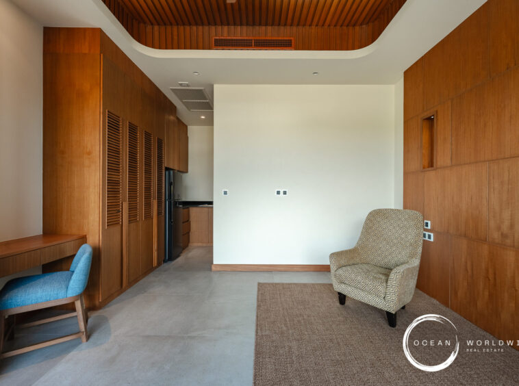 Contemporary living area with floor-to-ceiling wood panels, a blue upholstered desk chair, and a patterned armchair in the foreground.