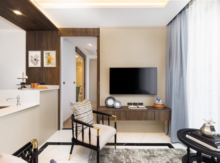 Modern living area with wood paneling, a wall-mounted TV, and a desk; blue curtains on the right.