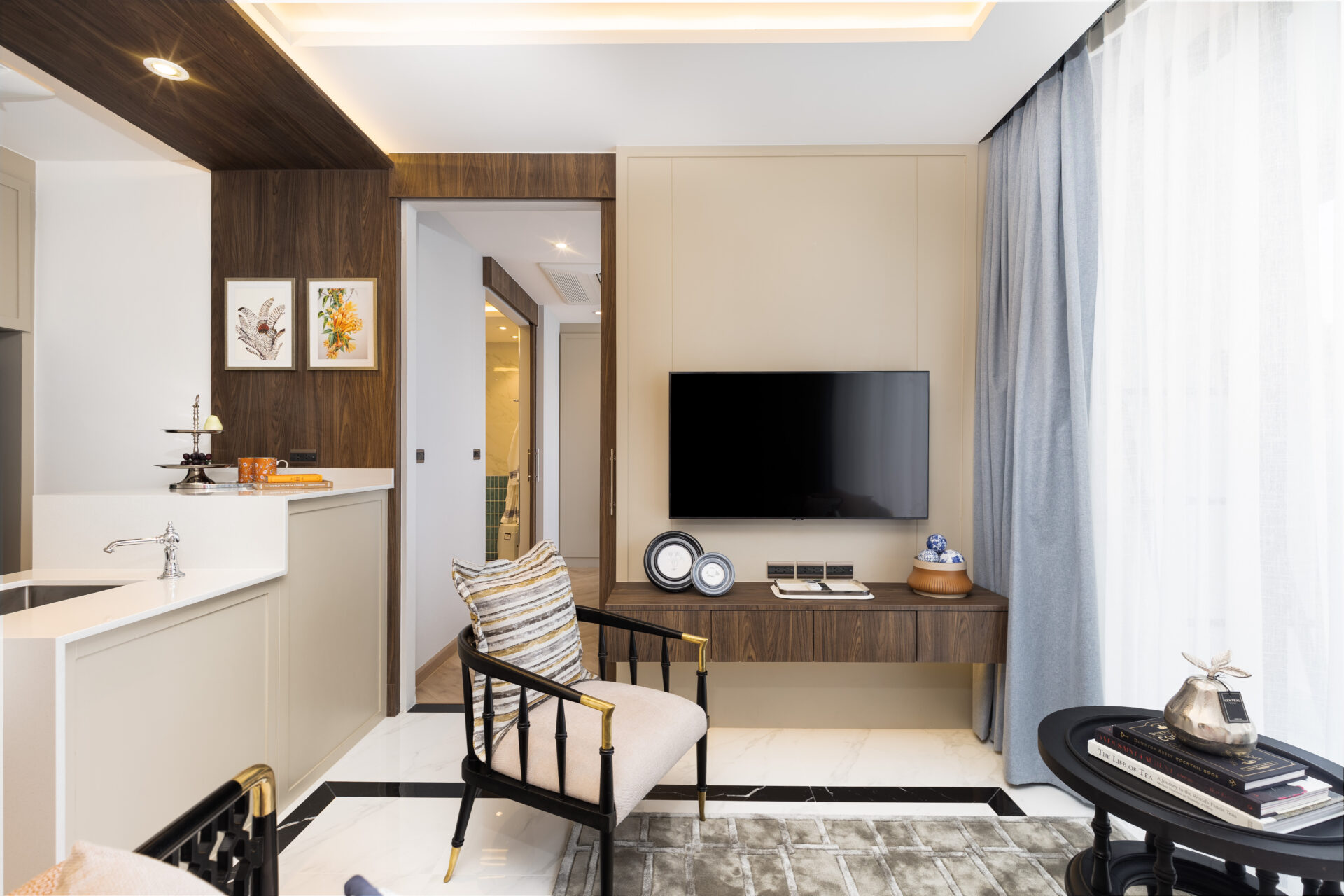 Modern living area with wood paneling, a wall-mounted TV, and a desk; blue curtains on the right.
