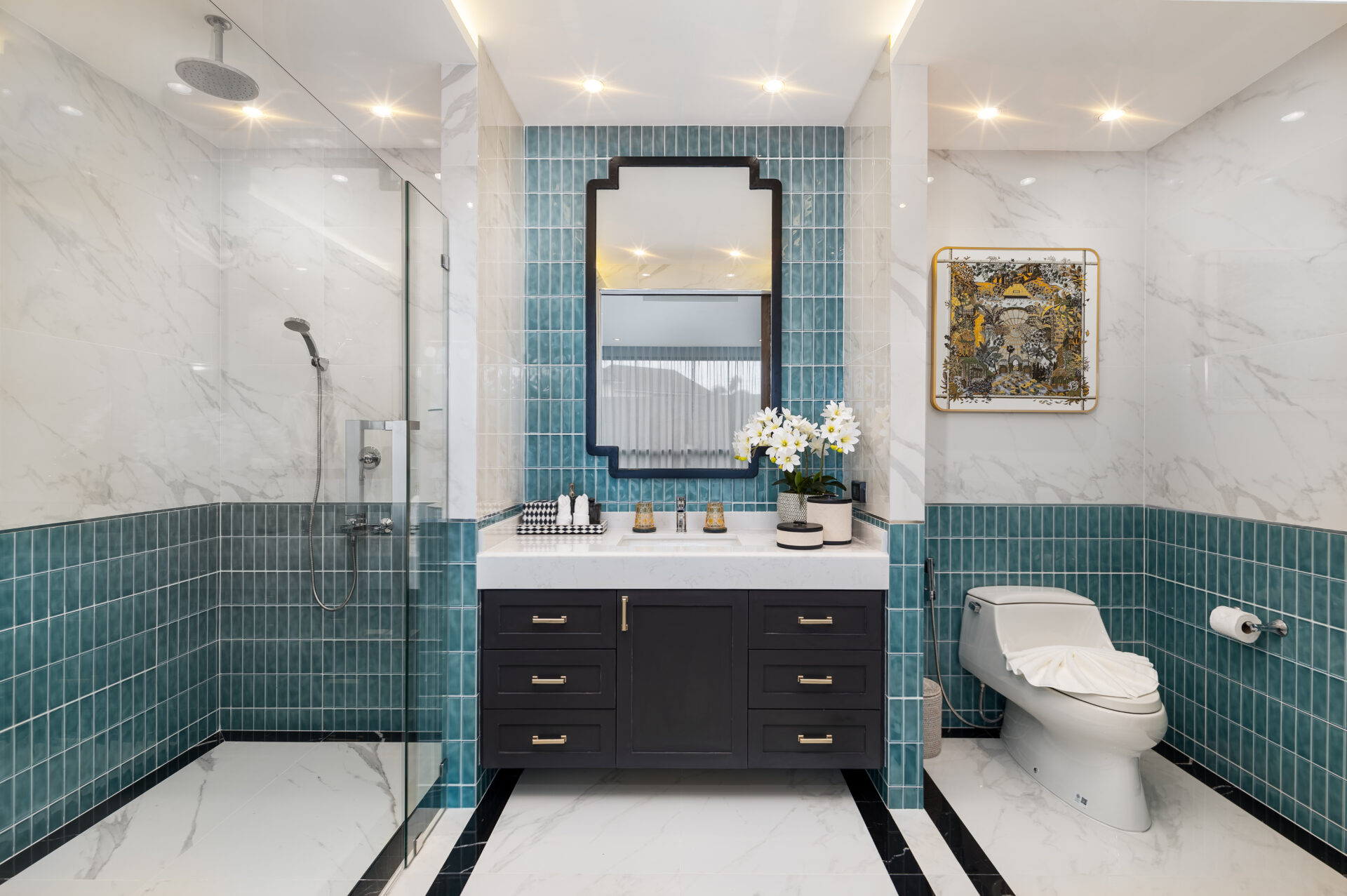 Luxurious bathroom with teal tile accents, a black double-drawer vanity, and a mirror above a marble countertop with white flowers and accessories.