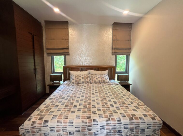 A neatly made double bed with a patterned duvet flanked by two dark wooden nightstands in a modern bedroom.