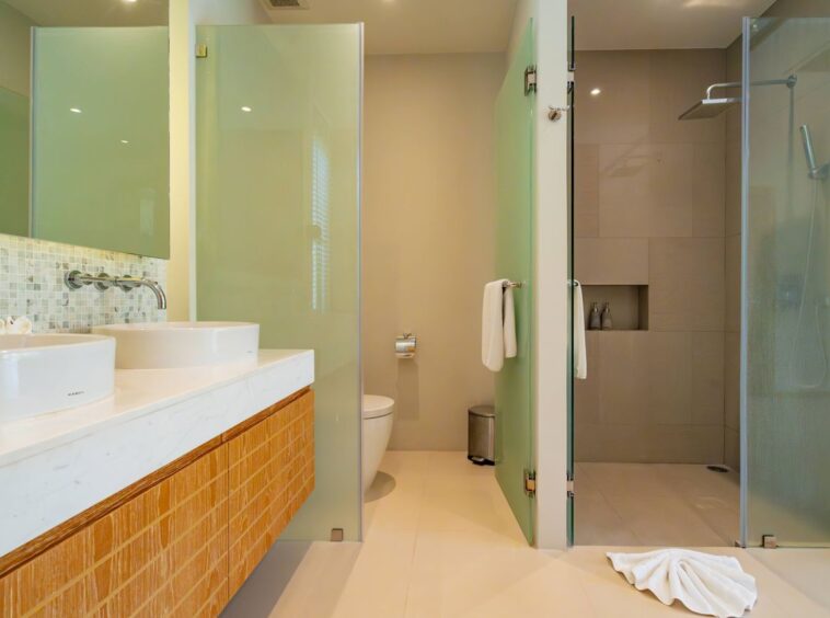 Modern bathroom with a double vanity, two round vessel sinks, and a glass-enclosed shower area.