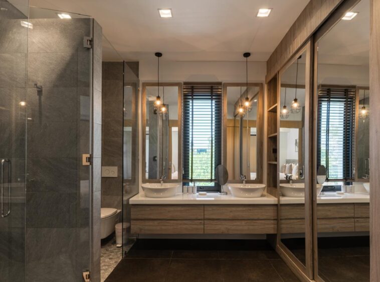 Modern bathroom with two vessel sinks, large mirrors, and a glass-walled shower.