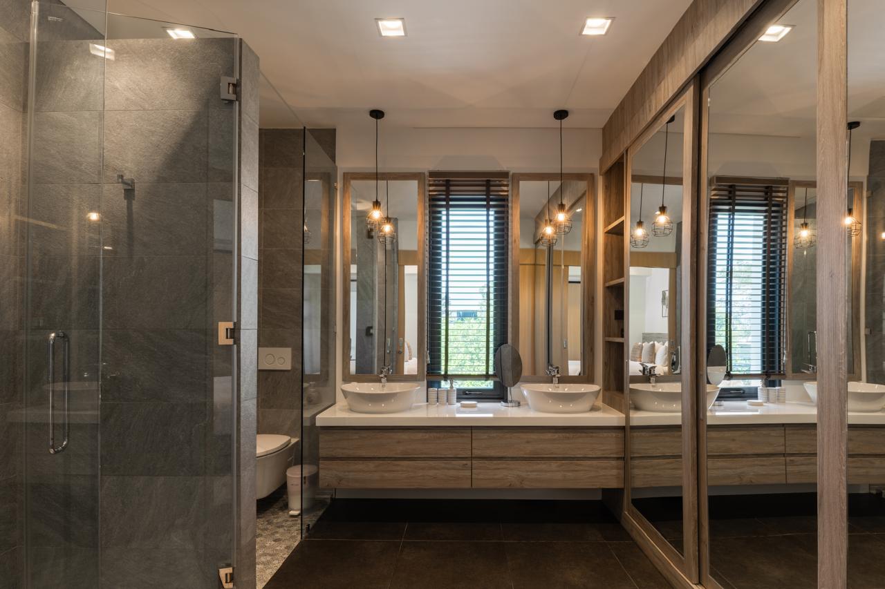 Modern bathroom with two vessel sinks, large mirrors, and a glass-walled shower.
