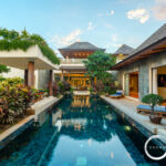 Luxurious resort pool courtyard with tropical plants, lounge chairs, and open-air seating areas.