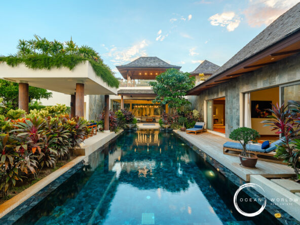 Luxurious resort pool courtyard with tropical plants, lounge chairs, and open-air seating areas.