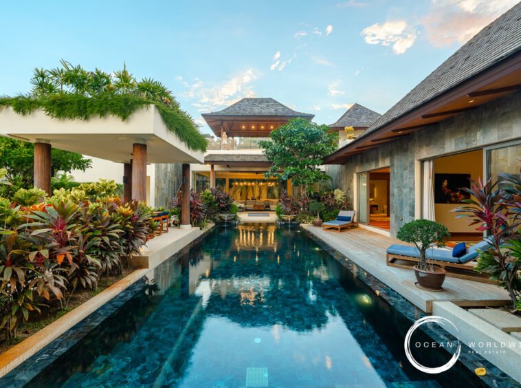 Luxurious resort pool courtyard with tropical plants, lounge chairs, and open-air seating areas.