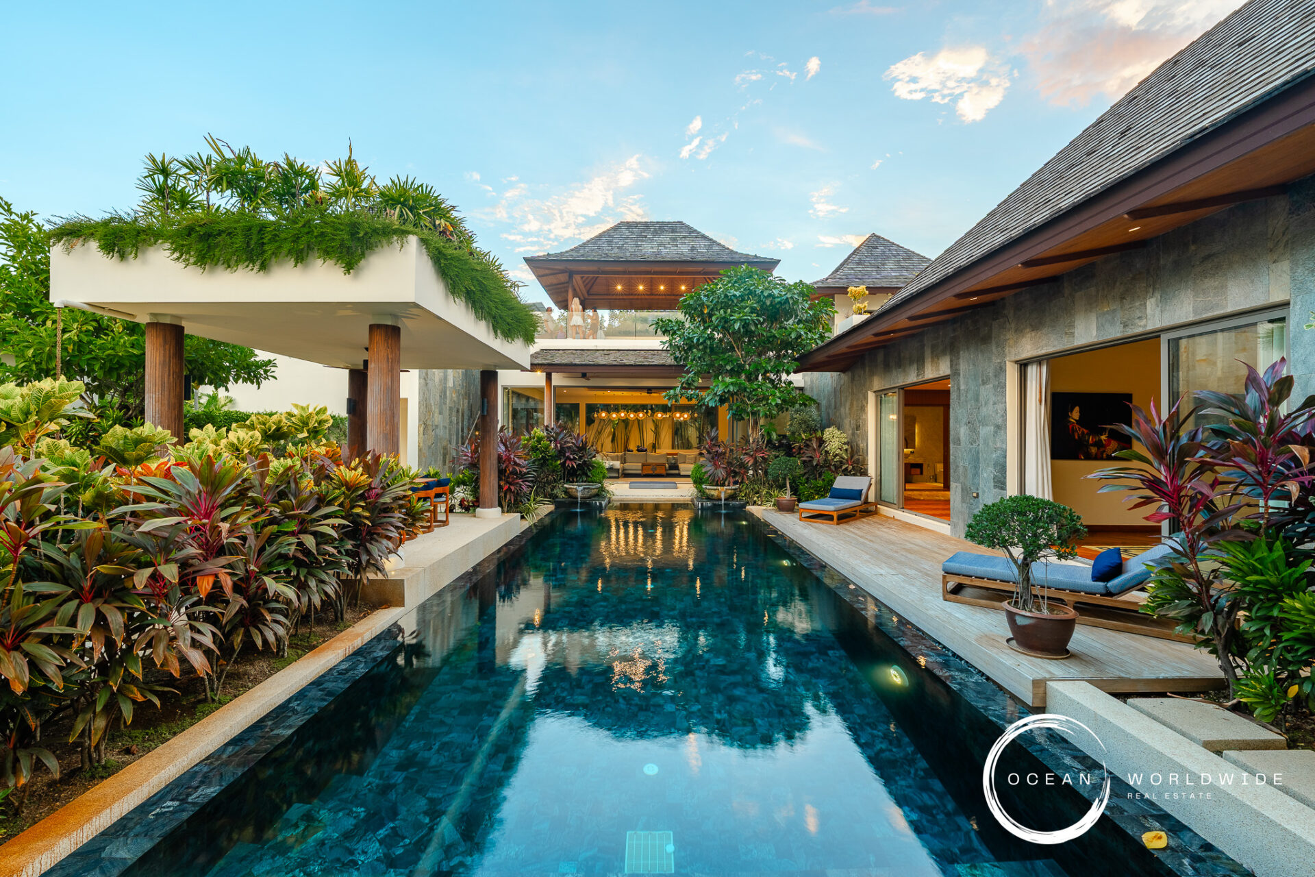 Luxurious resort pool courtyard with tropical plants, lounge chairs, and open-air seating areas.