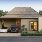 Modern single-story house with a wooden shingle roof; driveway under a carport holds a white sedan and a black SUV, surrounded by tropical plants.