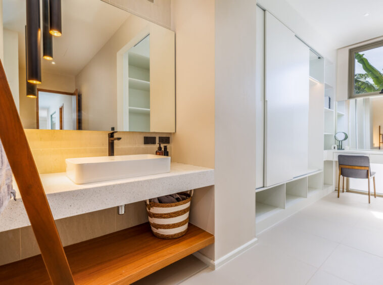 Modern bathroom with a white vessel sink, black faucet, and large mirrored cabinet above a speckled countertop.