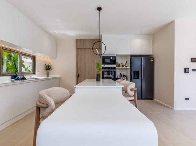 Bright modern kitchen with white cabinets, a center island, and a stainless steel fridge; circular pendant light hanging over the island.