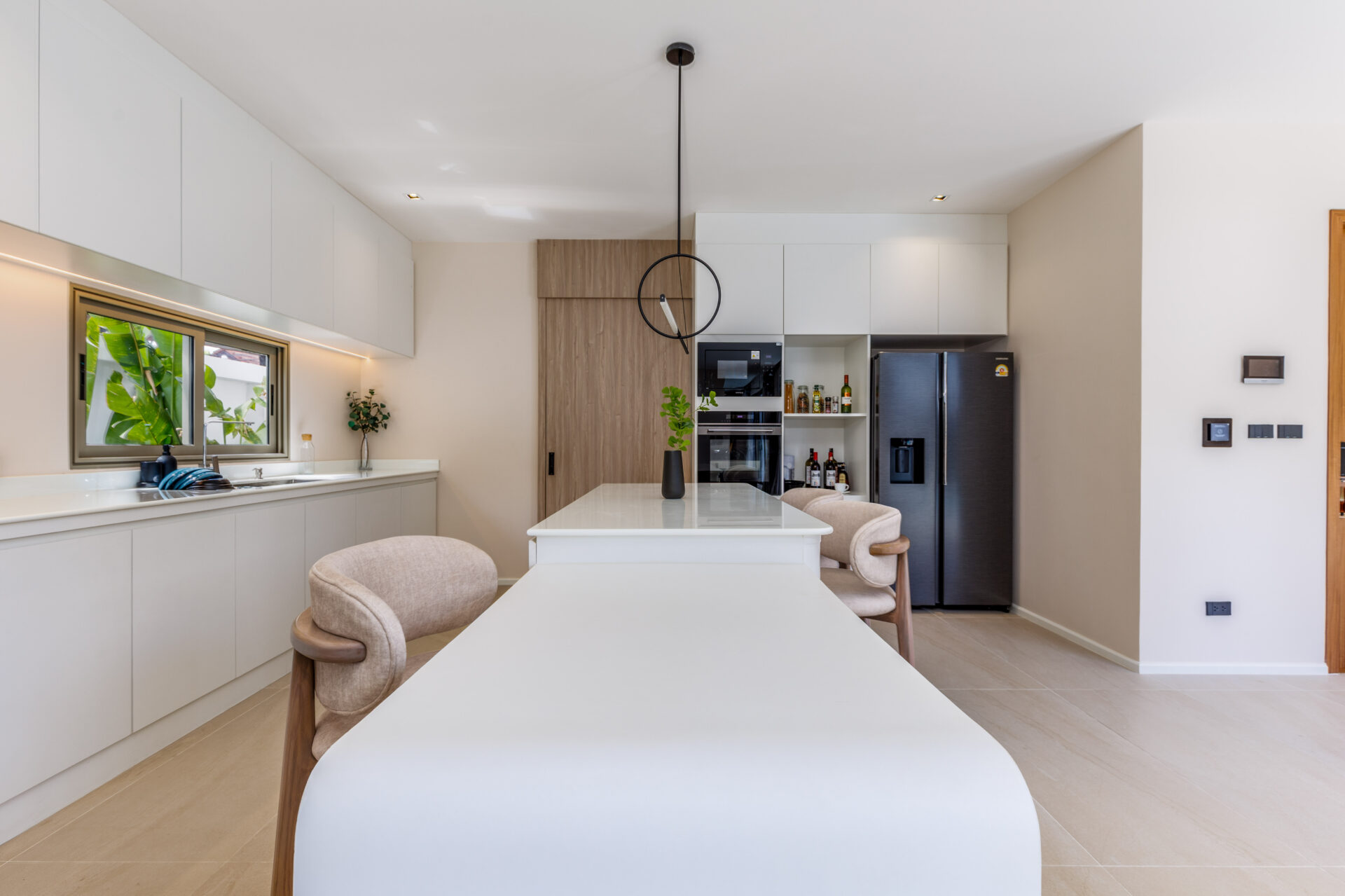 Bright modern kitchen with white cabinets, a center island, and a stainless steel fridge; circular pendant light hanging over the island.