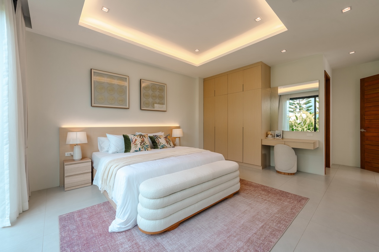 Bright modern bedroom with a king bed, two nightstands, matching lamps, a wood bench at the foot, and a large built-in wardrobe on the right.