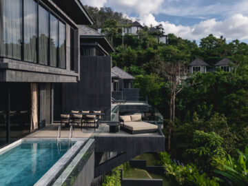 Modern hillside resort with glass-walled balconies and a poolside terrace overlooking lush greenery.