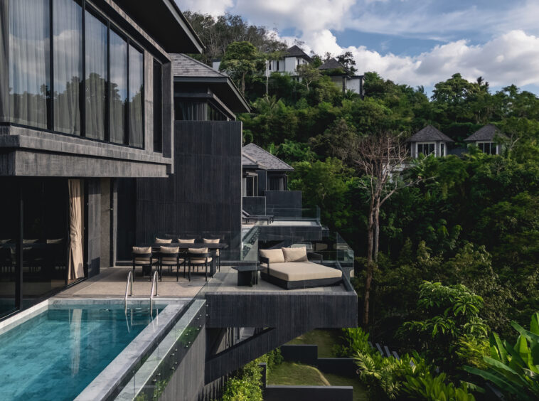 Modern hillside resort with glass-walled balconies and a poolside terrace overlooking lush greenery.