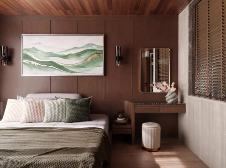Wood-paneled bedroom with a green landscape painting, two wall lamps, and a mirror on the right side.