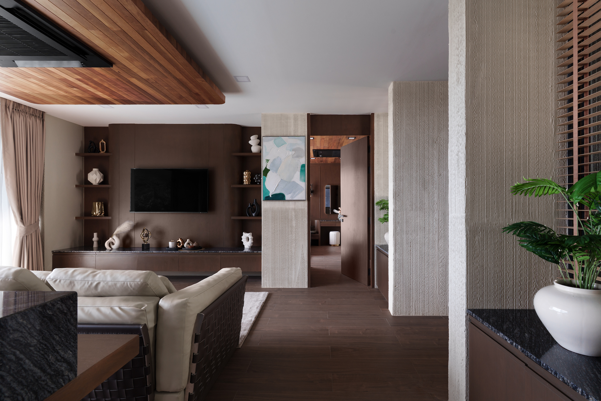 Modern living room with brown wood accents, built‑in shelves, and a wall‑mounted TV with decorative objects on shelves.