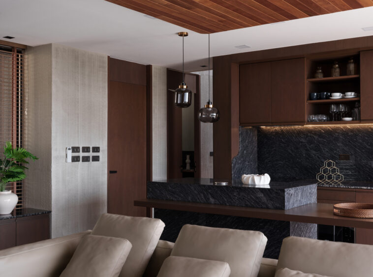 Open-plan kitchen and living area with dark wood cabinets, black marble island, and modern pendant lights.