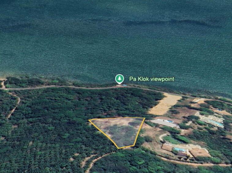 Aerial view of a coastal area with a yellow-outlined triangular land parcel among trees near Pa Klok viewpoint.