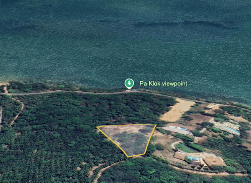 Aerial view of a coastal area with a yellow-outlined triangular land parcel among trees near Pa Klok viewpoint.