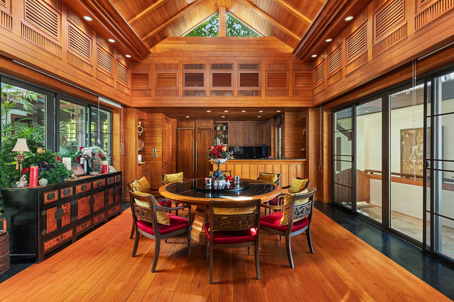Luxurious wood-paneled dining room with a round wooden table and cushioned chairs, flanked by tall cabinets and large glass doors