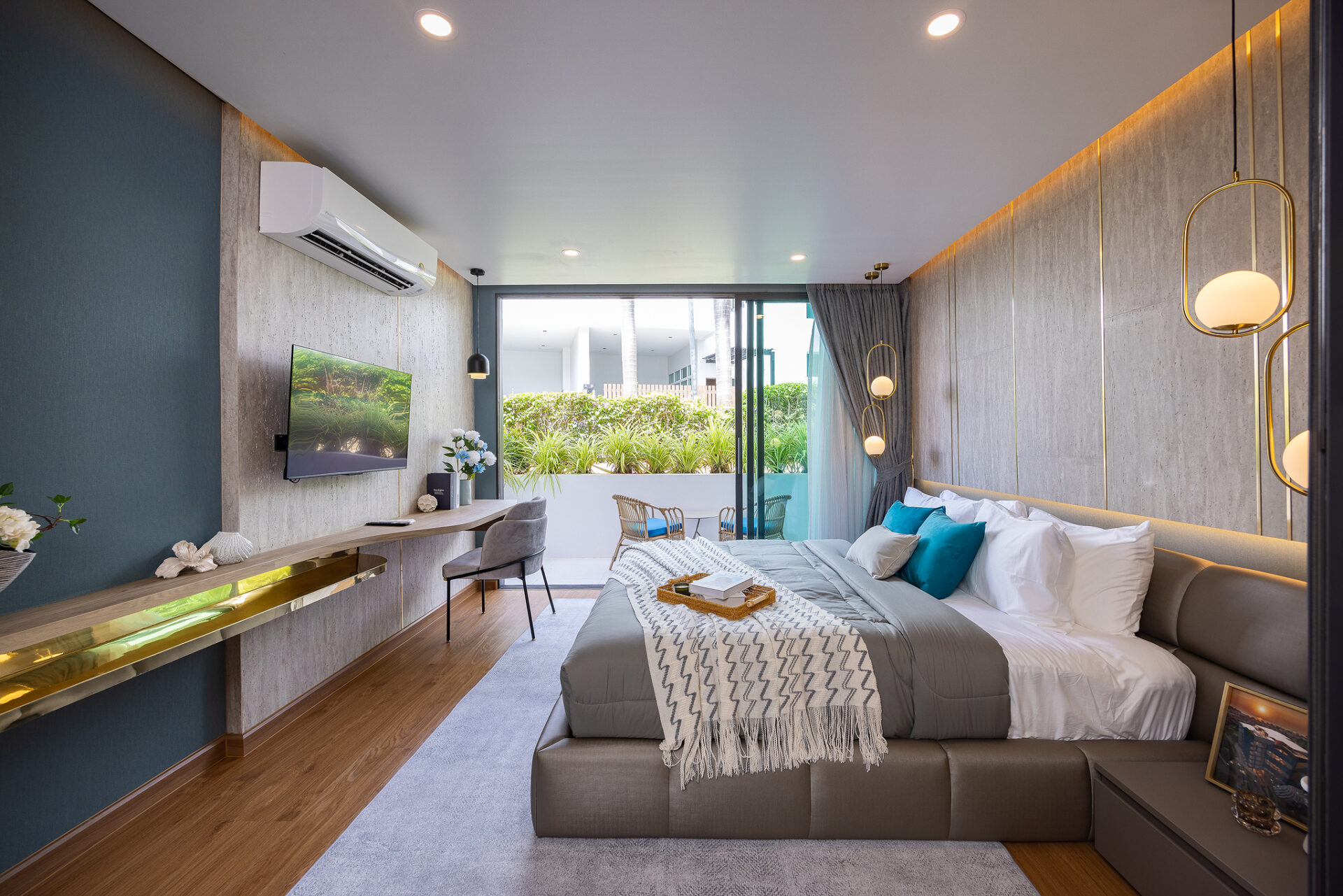 Modern hotel bedroom with a king bed, gray tones, teal accent wall, and wall-mounted TV overlooking a garden balcony.