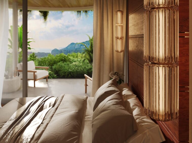 Hotel bedroom with beige bedding, copper ribbed column lamps, and a view of lush greenery and distant mountains through glass doors.