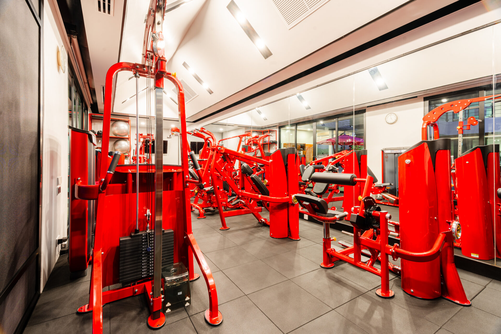 Red multi-station strength training machines in a bright gym.