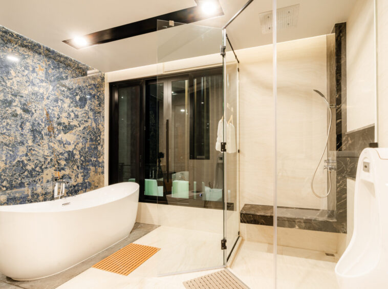 Contemporary bathroom with a white freestanding tub, glass shower, and blue marble accent wall.