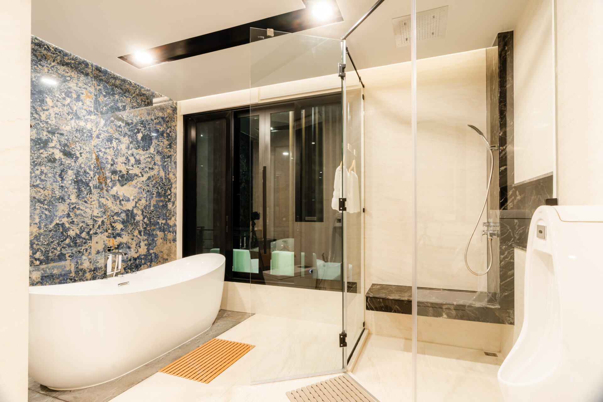 Contemporary bathroom with a white freestanding tub, glass shower, and blue marble accent wall.