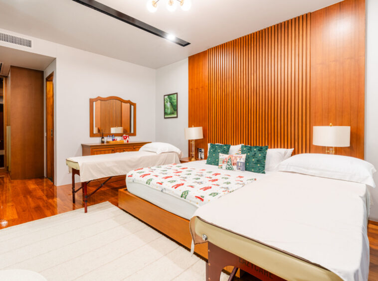 Hotel room with two queen beds, Christmas-themed throws and pillows, and a tall wooden headboard wall