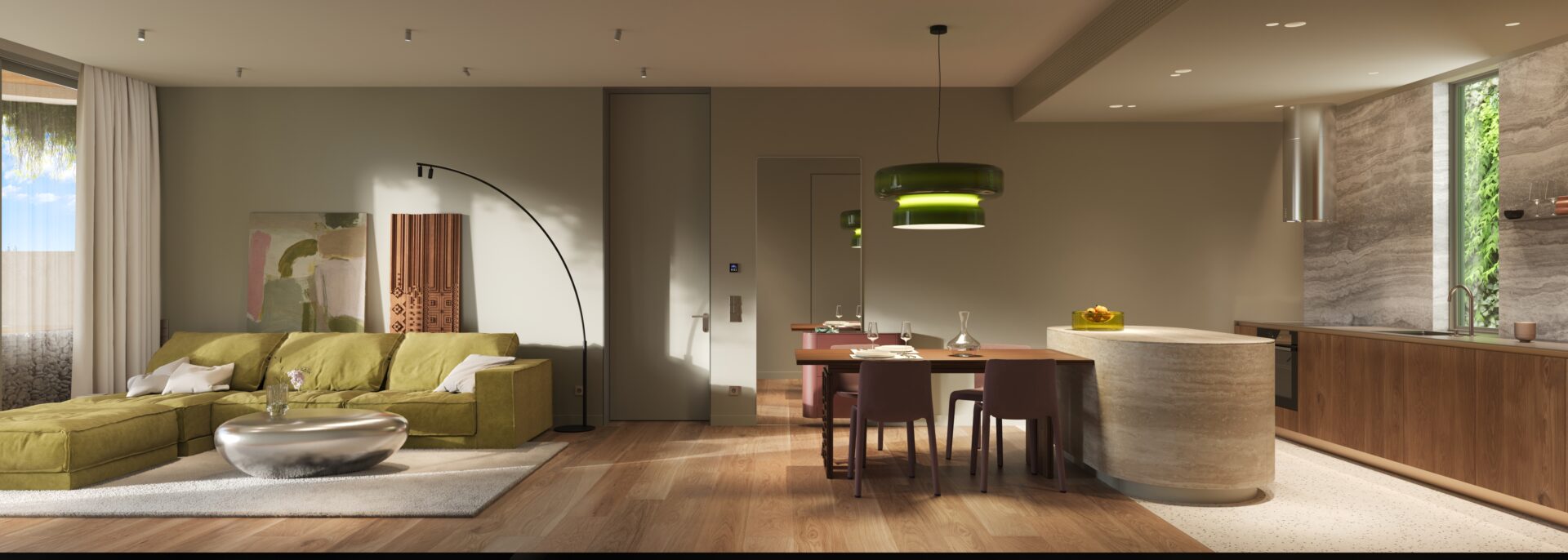 Open-plan living and dining area with a green sectional sofa, abstract art, and a curved floor lamp beside a doorway, leading to a modern kitchen island.