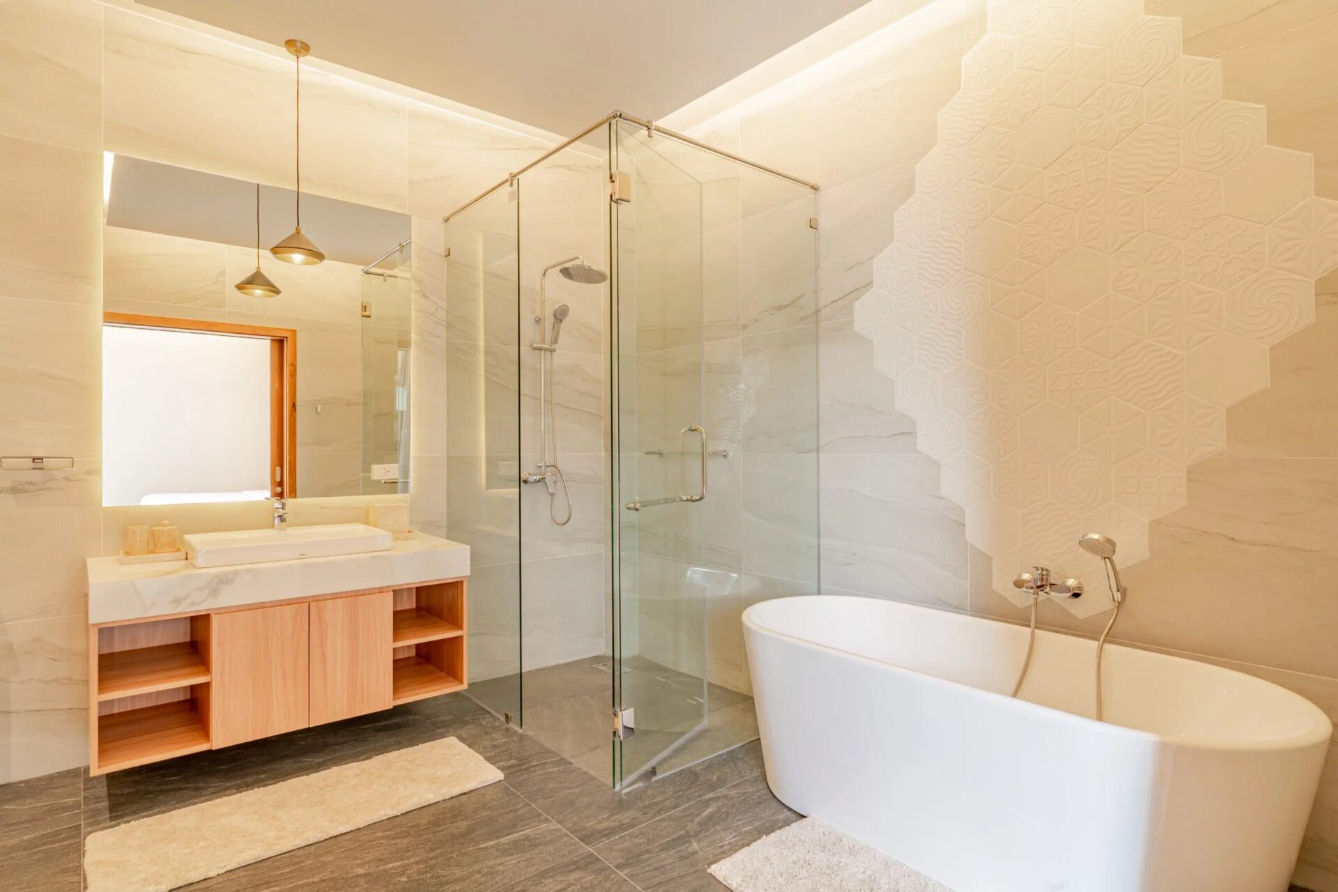 Bright modern bathroom featuring a glass-enclosed shower, freestanding tub, and a light wood vanity with marble countertop.