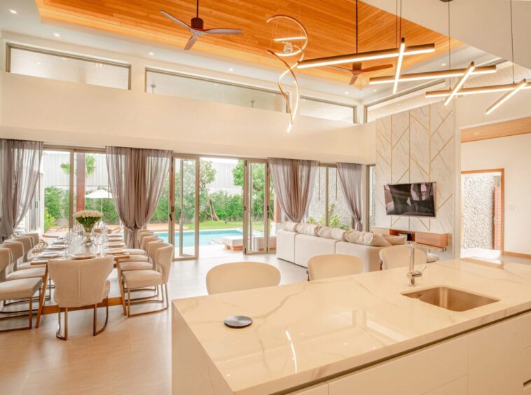 Open-plan living and dining area with a marble kitchen island, large glass doors, and a view of the pool outside.