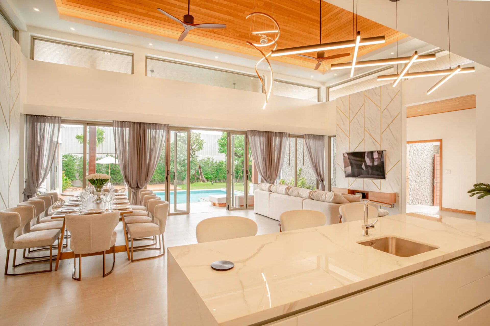 Open-plan living and dining area with a marble kitchen island, large glass doors, and a view of the pool outside.