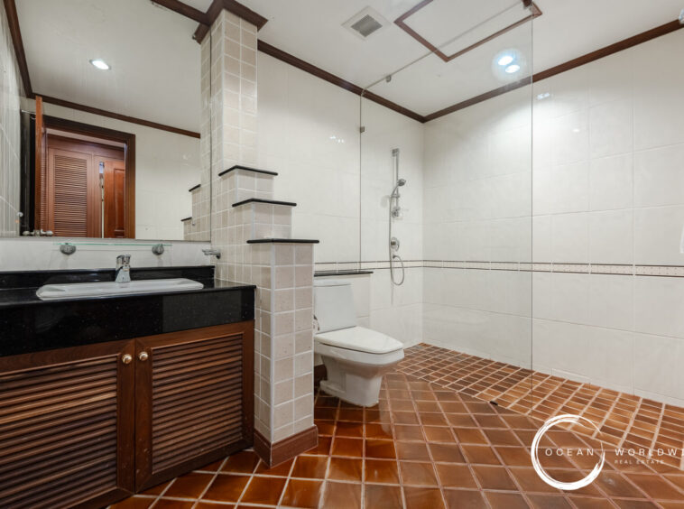 Bathroom with a wooden vanity, black countertop sink, large mirror, and glass shower enclosure.