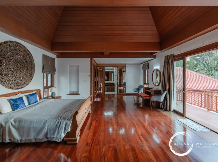 Luxurious bedroom with a wooden vaulted ceiling, king-size bed, blue pillows, and an ornate circular wall carving above the headboard.