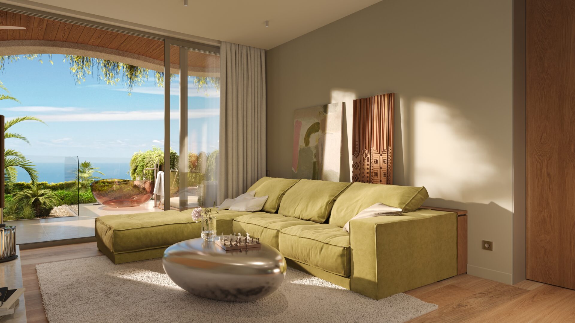 Living room with a green sectional sofa, glass doors to a sunny balcony, and ocean view beyond plants outside.