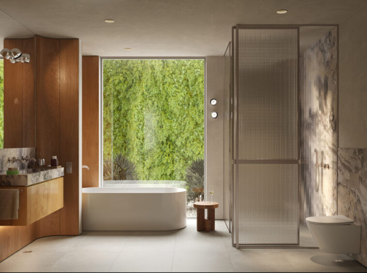 Modern bathroom with a freestanding white tub, wood cabinets, and a glass shower enclosure beside a large window overlooking greenery.